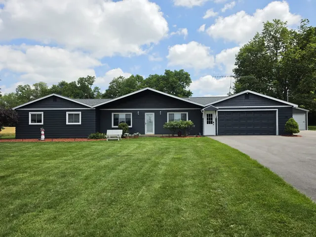 Ranch-style home painted dark navy with white trim, garage and a mowed front lawn