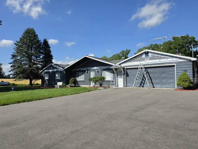 Ranch home with an attached garage and a ladder against the wall during an exterior painting project